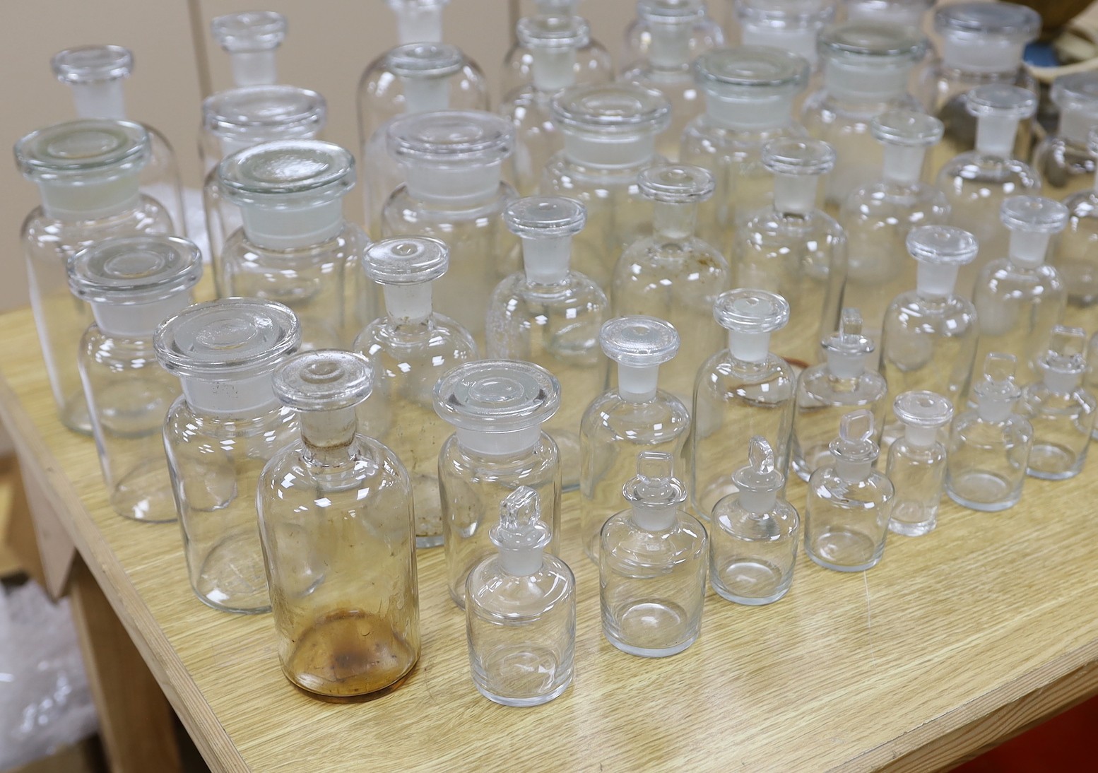 A large collection of clear glass chemist's bottles